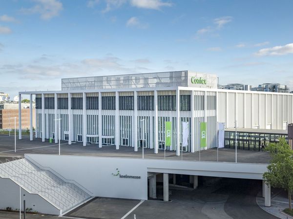 New Congress Center Confex from the outside: A large, white, modern building with a glass front and tall columns in front, as well as stairs leading to the elevated building!