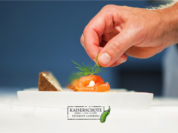 A hand garnishes salmon with dill. Cover of Kaiserschote Catering.