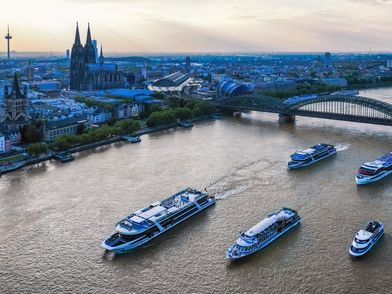 Der Rhein von Oben mit 5 fahrenden Eventschiffen, der Hohenzollernbrücke im Hintergrund und dem Kölner Dom mit Rheinufer an der Seite