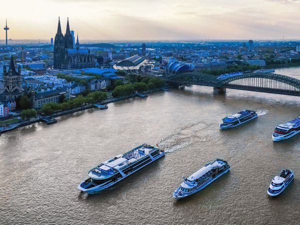 Der Rhein von Oben mit 5 fahrenden Eventschiffen, der Hohenzollernbrücke im Hintergrund und dem Kölner Dom mit Rheinufer an der Seite