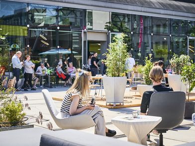 Outdoor area of Design Post Cologne: People sitting on lounge chairs among plants