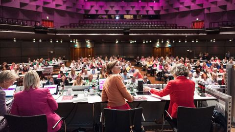Filled conference hall with four moderators on stage