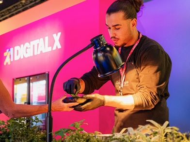 Nachhaltiges Catering auf der digital X: Ein Mann bereitet das Essen vor einem pinken digital X Stand vor.