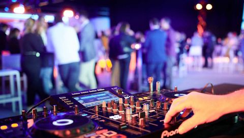 Event technology. DJ console and people standing in the background.