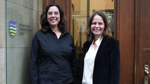 The two professors from the Rheinische Hochschule pose in the entrance area of the university.